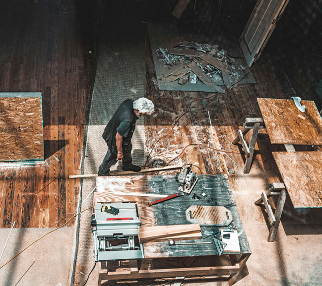 A master craftsman working at a saw table in the original Peter's woodworking shop, showcasing 50 years of joinery history.